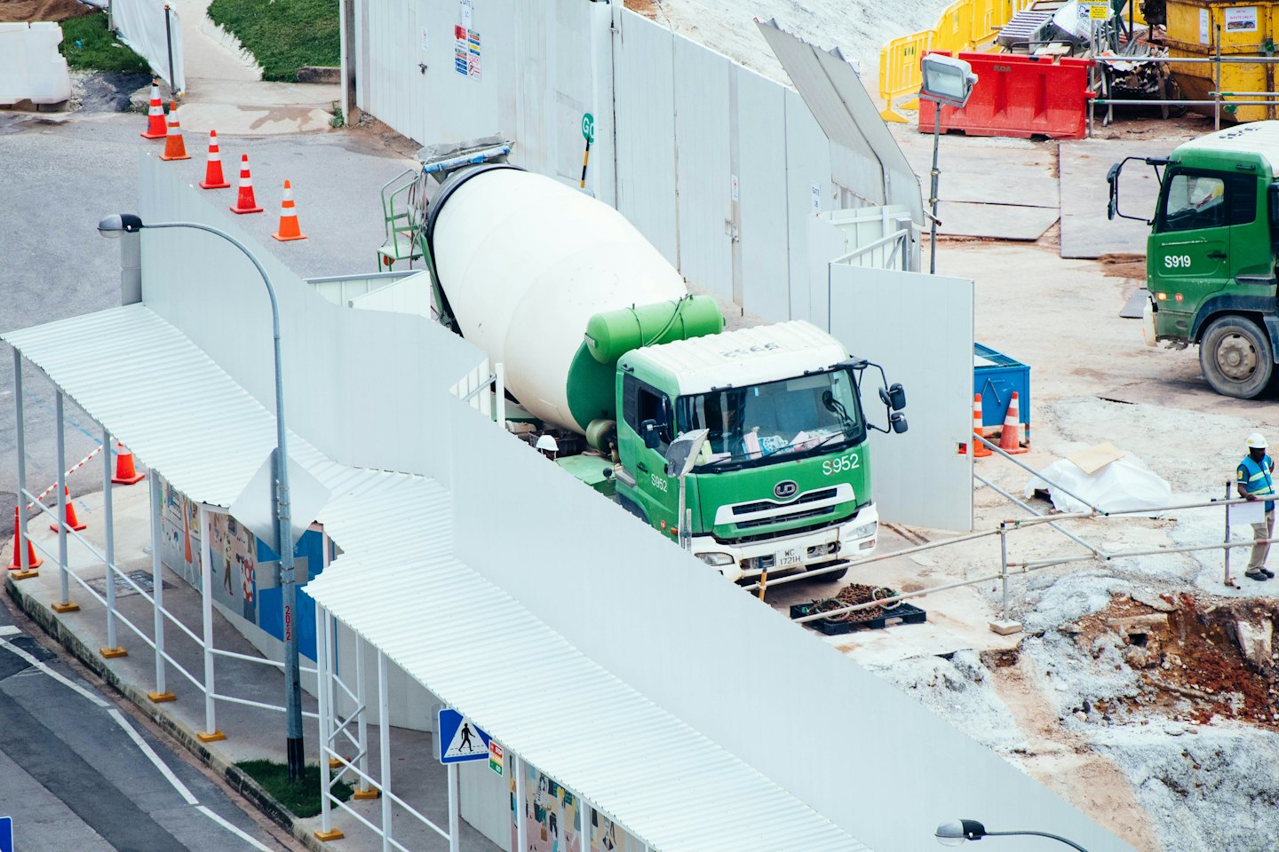 Construction worker with documents near cement mixer trucks.